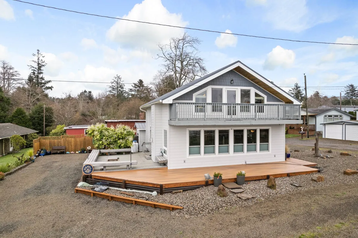 A wooden deck with large windows and a balcony overlooks the surrounding landscape. The space invites guests to relax outdoors, enjoy sunset views, or stargaze in the evenings, with a seamless connection between indoor comfort and outdoor beauty.