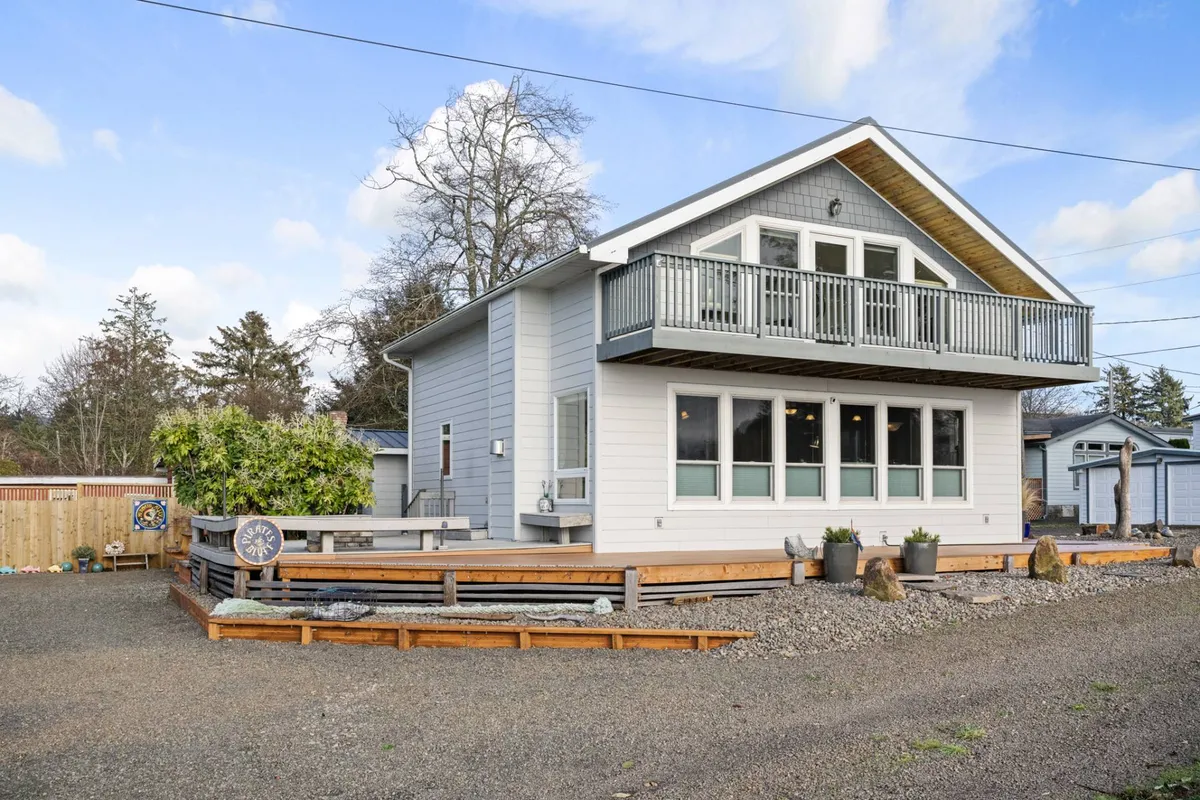The image shows a cozy balcony area with a landscaped garden below and the house’s exterior, creating an inviting scene of outdoor living. The balcony is perfect for relaxing, enjoying sunsets, or unwinding after a day of coastal exploration.