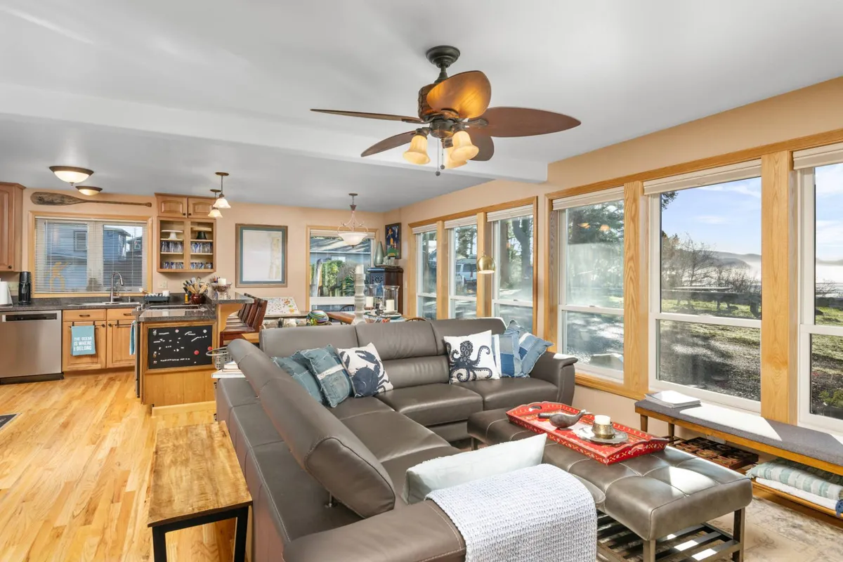An inviting interior space with large windows overlooking the outdoors, a comfortable seating area, and a modern kitchen. The setting feels open and serene, ideal for families or groups to gather, relax, and enjoy privacy.